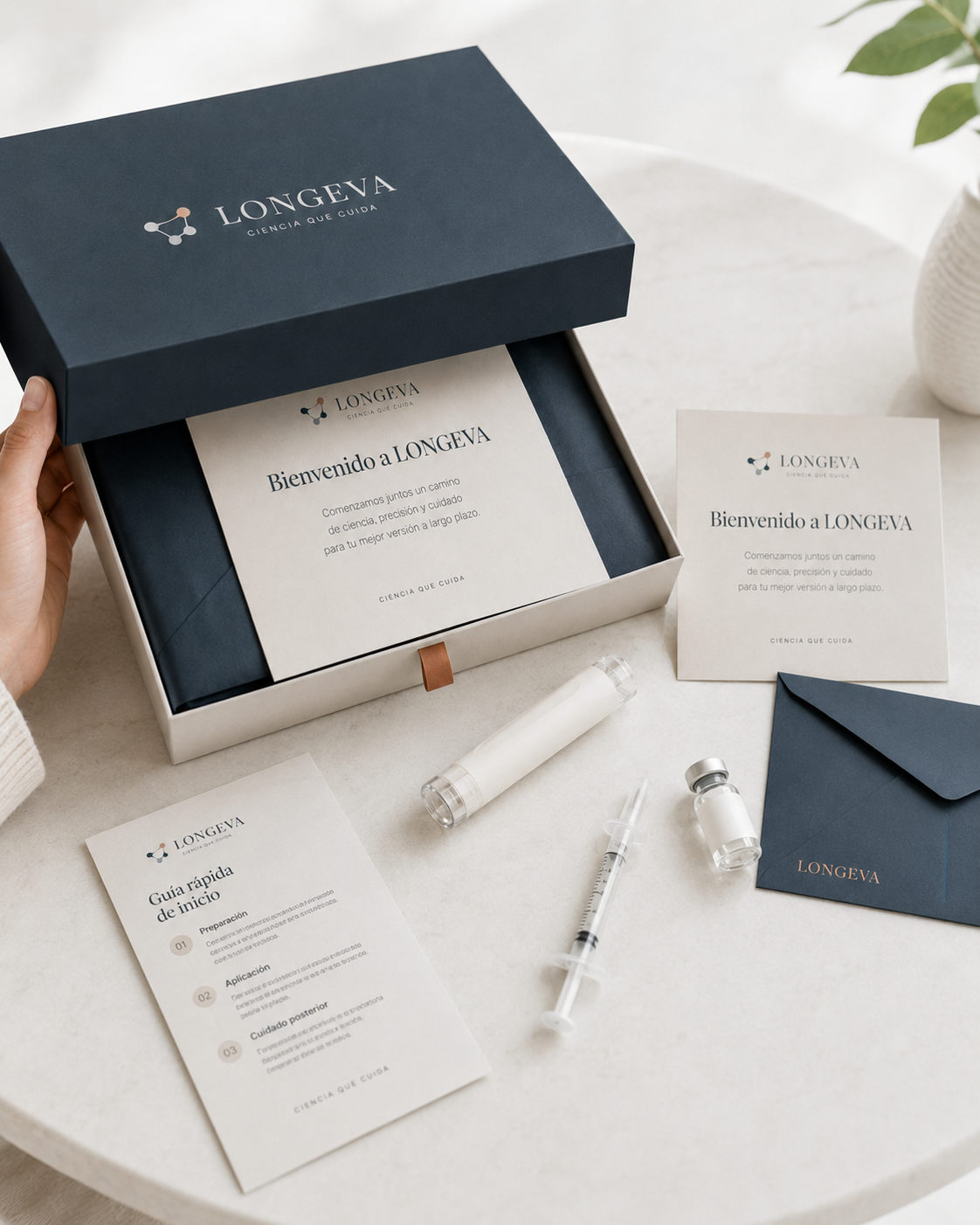 Kit de inicio LONGEVA abierto sobre una mesa: caja de bienvenida, tarjeta de inicio, guía rápida, jeringa y frasco